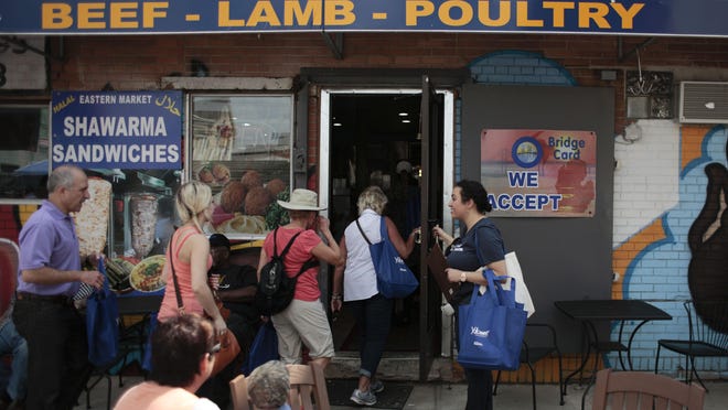 Tour guide Sonya Kassis from Garden City holds the door at the Eastern Market Mediterranean Grill and Market for tour participants during the Arab American Tour of Eastern Market on Saturday, May 30, 2015 at the Eastern Market in Detroit. Tim Galloway/Special to DFP