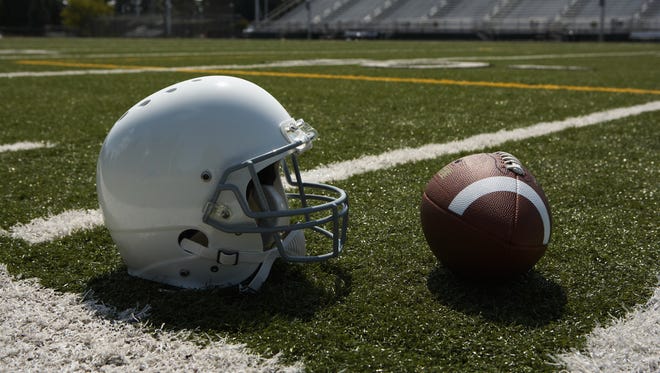 Football and football helmet on football field