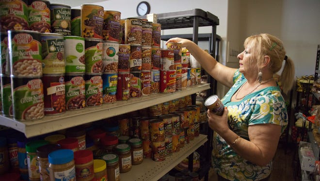 Fila Bukowiecki, who works for the community resource center, organizes food in the main pantry of the Switchpoint Poverty Resource Center Wednesday, Sept. 3, 2014.
