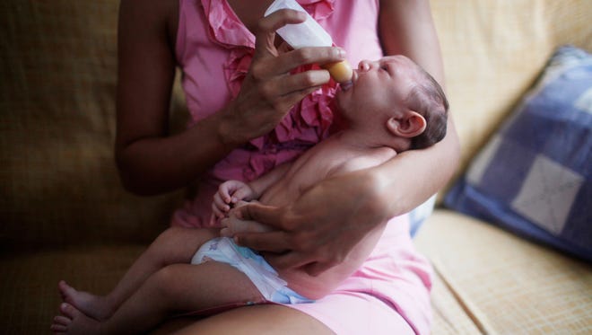 Daniele Santos feeds her baby, Juan Pedro, 2-months-old, in their living room on February 3, 2016 in Recife, Brazil.