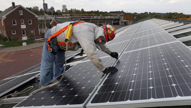 A contractor installs solar panels a shed at the city-owned Public Market. (2012 photo)