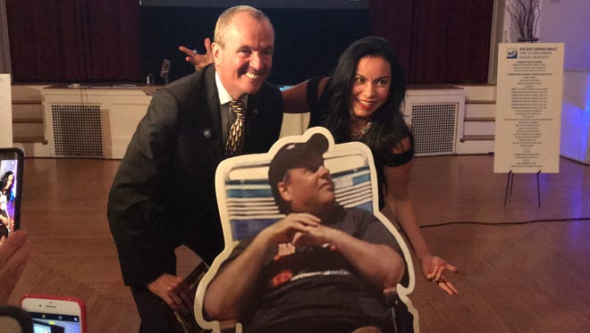 Gov.-elect Phil Murphy stands behind a cutout of Chris Christie in a beach chair with Analilia Mejia of the New Jersey Working Families Alliance at an event on Thursday.