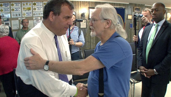 A New Jersey State Trooper assigned to the Executive Protection Unit (right) stays close to NJ Governor and Republican presidential candidate Chris Christie as he meets Tom Hamlin, Laconia, NH, after a town hall meeting at the Ashland, NH, American Legion Hall Wednesday, July 1, 2015.