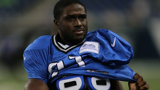 Detroit Lions running back Reggie Bush puts on his jersey before practice Aug. 6, 2014.
