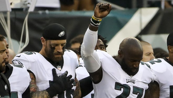 The Eagles' Chris Long (56) stands beside Malcolm Jenkins as he raises his fist during the national anthem