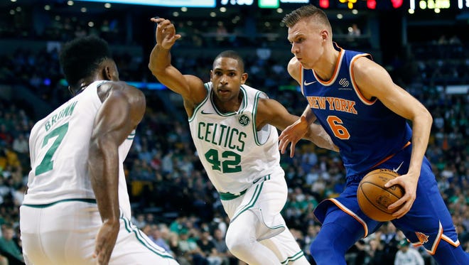 New York Knicks' Kristaps Porzingis (6) drives for the basket against Boston Celtics' Al Horford (42) and Jaylen Brown (7) during the first quarter of an NBA basketball game in Boston, Tuesday, Oct. 24, 2017.