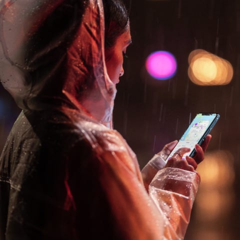 Woman using iPhone XR in the rain at night