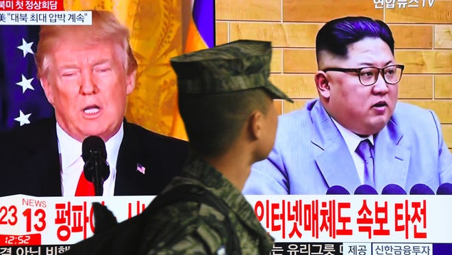 A South Korean soldier walks past a television screen showing pictures of President Trump and North Korean leader Kim Jong Un at a railway station in Seoul.