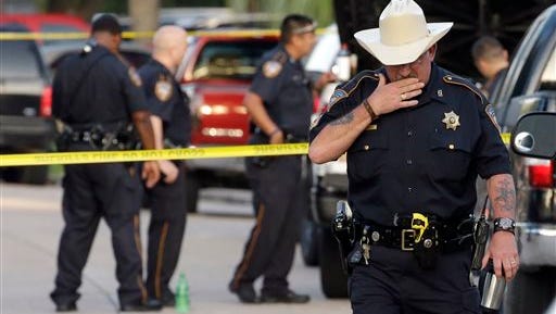 Harris County Sheriff's Department Sgt. D.J. Hilborn, right, walks away from the scene of a multiple shooting Sunday, Aug. 9, 2015, in Houston. Eight people, including five children and three adults, were found dead late Saturday inside a Houston-area home following the arrest of a man who exchanged gunfire with police, Texas authorities said Sunday.