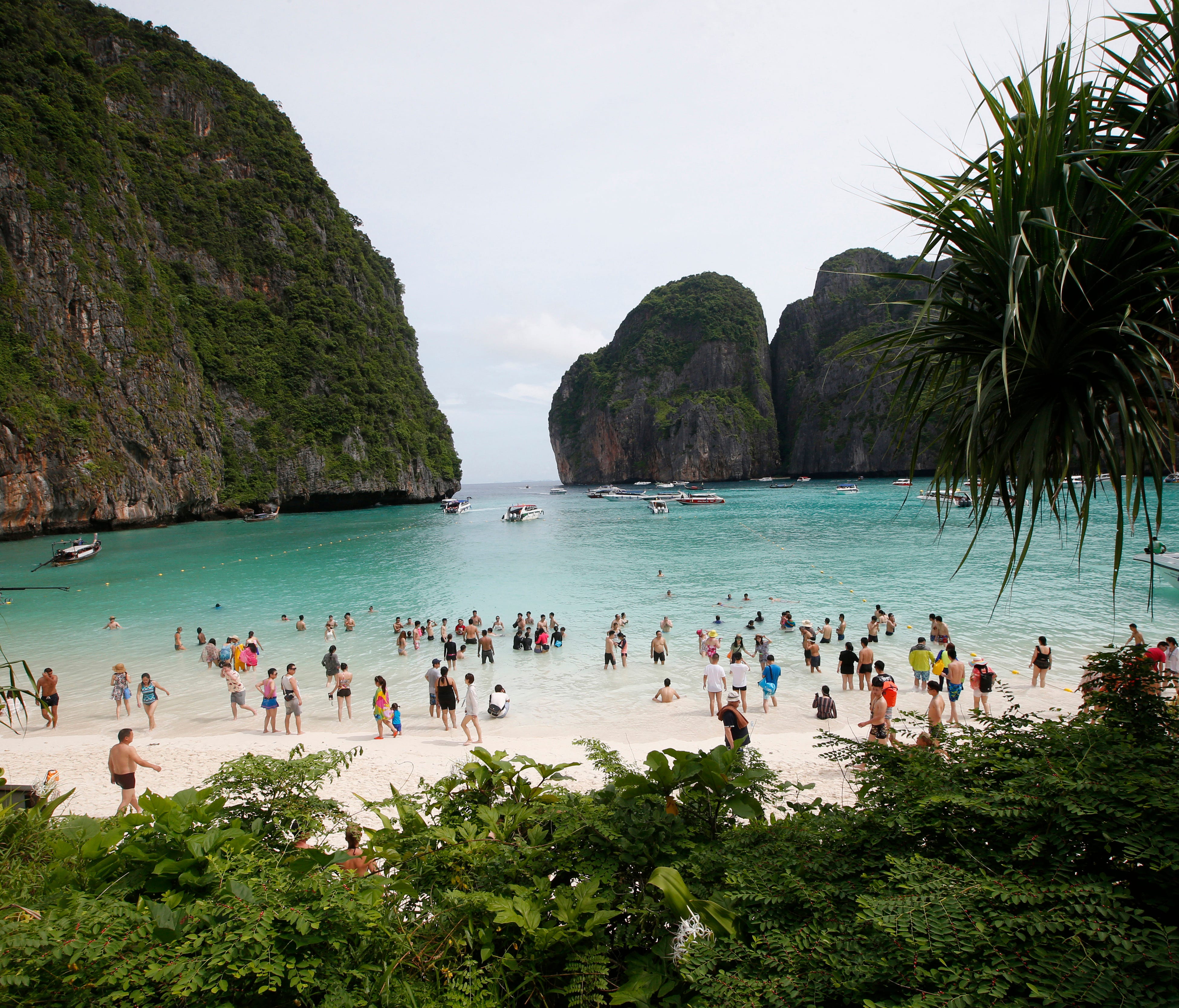 Tourists walk the beach of Maya Bay in Thailand on May 31, 2018. The popular tourist destination in the Andaman Sea will close to tourists for four months to give its coral reefs and sea life a chance to recover from an onslaught that began nearly tw