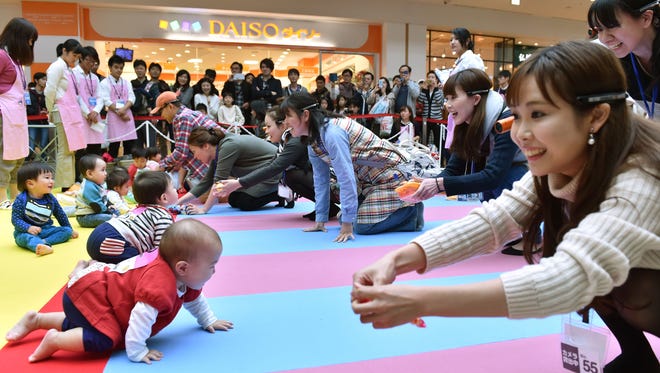 Babies compete in a baby crawling competition hosted by a Japanese magazine e on November 23, 2015. The competition was held to challenge the Guinness World Record for the largest crawling competition with the maximum number of participants.