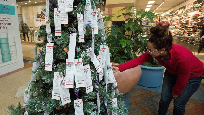 Adriana Sanchez looks over the "Be a Santa to a Senior Tree" where she was deciding which recipient she would sponsor and buy gifts for, Tuesday Nov. 21, 2017.