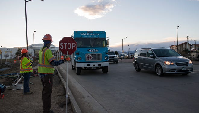 Flagger Karissa Crooks, left, and traffic control supervisor Ira Harris direct traffic under the Interstate 25 underpass that is currently under construction on Wednesday, Dec. 20, 2017, in Loveland, Colo.