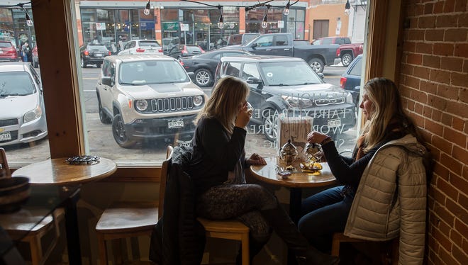 Fort Collins residents Leann Brown, right, and Nancy Namuth drink their tea while traffic passes by on Walnut Street on Wednesday, Dec. 27, 2017, at Happy Lucky's Teahouse in Fort Collins, Colo.