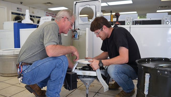 Father and son Ron and Reed Fears, co-owners of R & B Repair Co. in Flora, work together to repair the transmission inside the Speen Queen Commercial Washer at the Elton Road Coin Laundry.