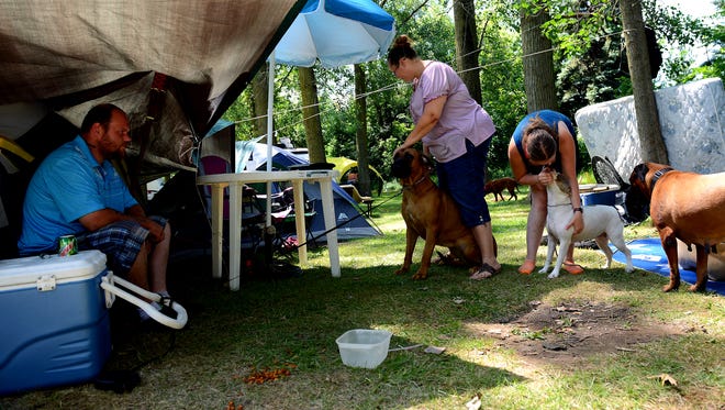Trisha Burch, center, holds her dog Mishka, as she and her family — husband Michael Abraham,  left, daughter Kaylee, 17, right, and sons Camden, 12, and Noah, 14, both unpictured — try to stay cool while camping at the Cottonwood Campground in Lansing, Friday, July 23, 2016.