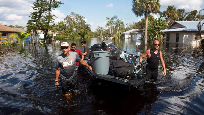 Don Manley, left, and Pedro Castellano, right, pull Manley's boat, loaded with resident's belongings, along a flooded Chapman Avenue in Bonita Springs on Friday, Sept. 15, 2017, five days after Hurricane Irma. 