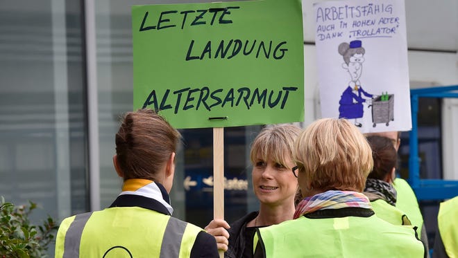 Lufthansa cabin crew protest during a strike at the airport in Duesseldorf, Germany, Monday , Nov. 9, 2015. The poster at left reads "last landing - poverty among the elderly".