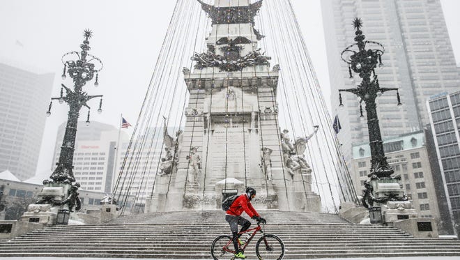 Lane Lyday rides his mountain bike on the Soldiers and Sailors Monument as snow falls in Indianapolis on Friday, Dec. 29, 2017. 