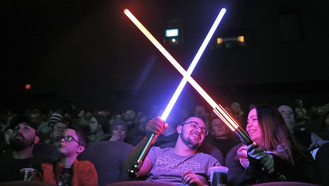 Star Wars fans, including Dustin Scott and Jennifer Bellville, trying out their lightsabers, wait for the start of the "Rogue One:  A Star Wars Story" showing at the Indiana State Museum IMAX Theater.