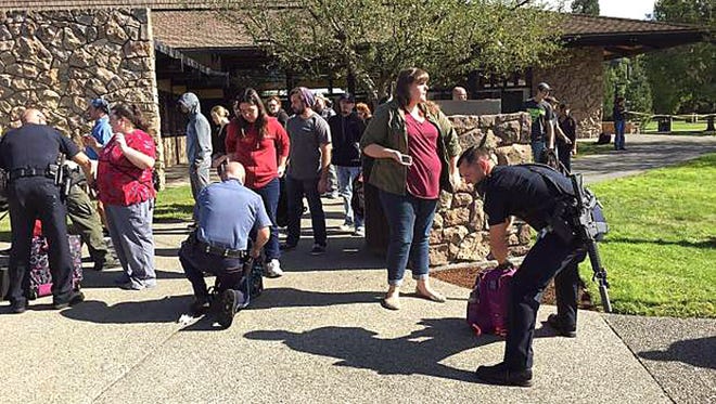 Police search students outside Umpqua Community College in Roseburg, Ore., Thursday, Oct. 1, 2015, following a deadly shooting at the southwestern Oregon community college. (Mike Sullivan/Roseburg News-Review via AP)