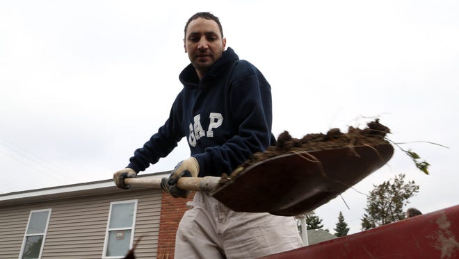 Sam Halawa, 40, of Dearborn adds dirt into a wheelbarrow at the front yard of the Habitat for Humanity home that will become his in November. 
He was one of over 20 volunteers that worked on Habitat for Humanity homes on Hartwell Street in Dearborn to help during "Make a Difference Day."
