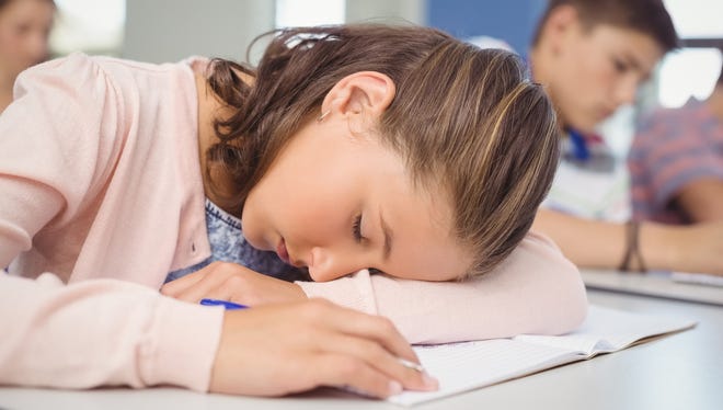 Tired student sleeping in classroom.