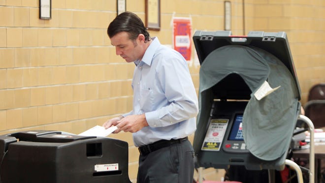 Micah Harding places his Kentucky primary ballot in a scanner at the polling place at St. Augustine Church in Covington.