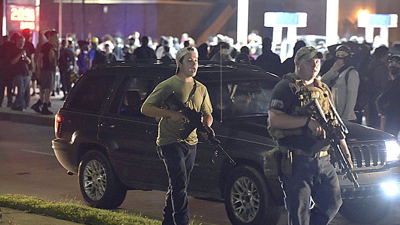 Kyle Rittenhouse, left, with backwards cap, walks along Sheridan Road in Kenosha, Wis., Tuesday, Aug. 25, 2020, with another armed civilian. Prosecutors on Thursday, Aug. 27, 2020 charged Rittenhouse, a 17-year-old from Illinois in the fatal shooting of two protesters and the wounding of a third in Kenosha, Wisconsin, during a night of unrest following the weekend police shooting of Jacob Blake.