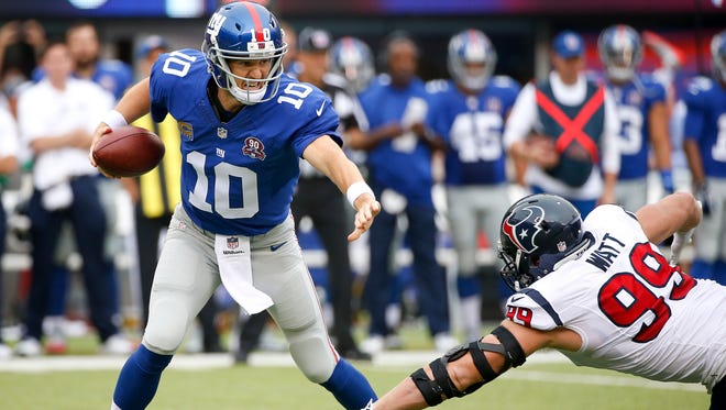 Giants quarterback Eli Manning, left, tries to avoid Houston Texans defensive end J.J. Watt in the first quarter on Sunday, in East Rutherford, N.J.