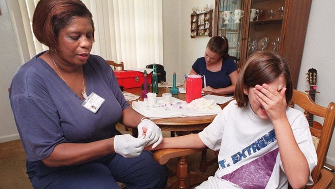 A nurse takes blood from a child to test for lead levels.