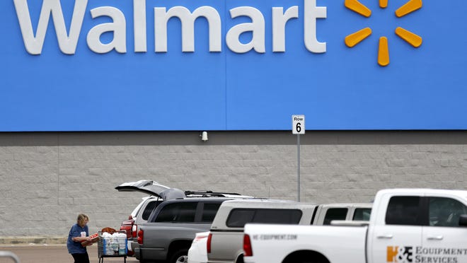 In this March 31, 2020 file photo, a woman pulls groceries from a cart to her vehicle outside of a Walmart store in Pearl, Miss.