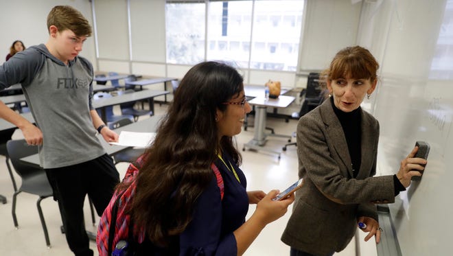 In this photo taken Oct. 11, 2017, Ellen Tara James-Penney, right, a lecturer at San Jose State University, talks with a student at the end of her English class on the university's campus in San Jose, Calif. Even teachers are among the working homeless in the booming economy along the West Coast.