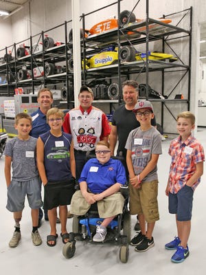 Riley champions and kids pose for a photo with John Andretti and his cousin Michael Andretti at the Andretti Autosport's shop, July 18, 2016, during a tour.