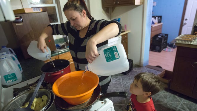 Lee Anne Walters of Flint pours gallons of bottled water into a bucket and pan to warm up for her two twin sons to take a weekly bath as her son Gavin Walters 4, looks on on Thursday October 1, 2015. Walters uses 8-10 gallons of bottled water to avoid her children's exposure to the Flint drinking water that contains high levels of lead since the city switched from getting their water from Detroit to use water from the Flint River. 'My family will never drink from a tap again. Never ever it's too scary,' Walters said.  