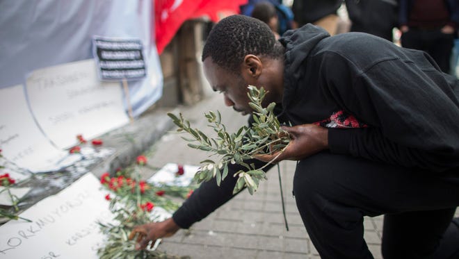 A foreigner places an olive branch at the scene after a suicide attack explosion in Istanbul on Istiklal Street on March 20, 2016. The attack occurred March 19, 2016. Five people died, including the suicide bomber.