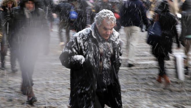 Pedestrians make their way through driving snow in midtown Manhattan in New York, Monday.