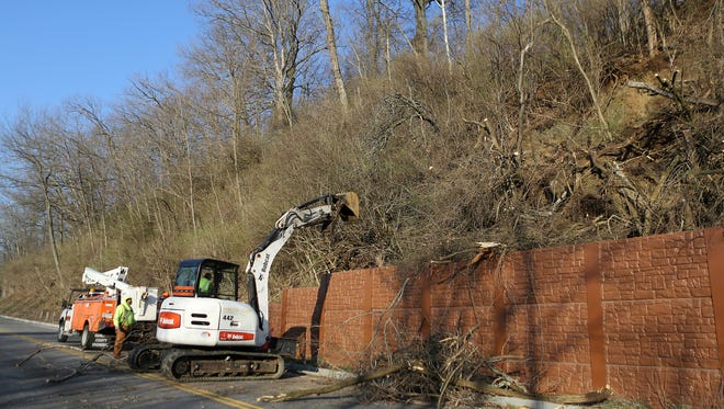 Workers remove trees after a landslide closed part of Loveland-Madeira Road in Indian Hill near Interstate 275.