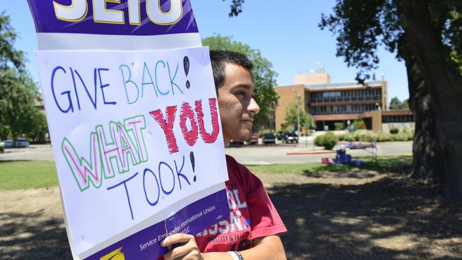 In this archive photo, Angel Torres holds a sign in front of the courthouse in Visalia. Members of Local 521, Service Employees International Union, protested against the county. On Tuesday, an appeal court sided with county workers who were ordered to receive pay raises and promotions.
