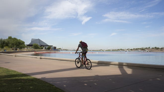 A bicyclist rides at Tempe Town Lake on April 27, 2016. Tempe said the lake's anticipated reopening will be delayed up to two weeks while testing on the new hydraulic dam continues.