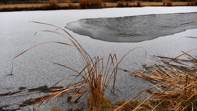 A dusting of snow covers the solid frozen surface of the lake at Cal Young Park Tuesday. Light flurries marked most of the day until the sun finally broke through around 3 p.m. Tuesday's high was 24 degrees but Wednesday's temperature is predicted to reach 46 degrees.