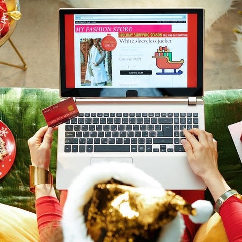 A woman online shopping surrounded by Christmas de