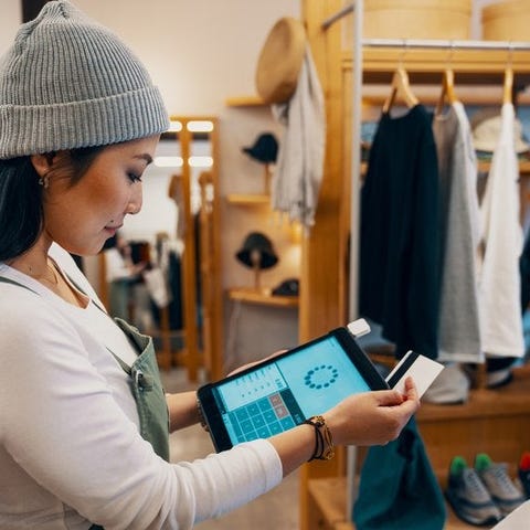 A female clerk at a clothing store swiping a credi
