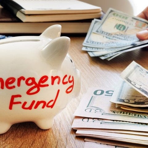 A white piggy bank that says emergency fund next t