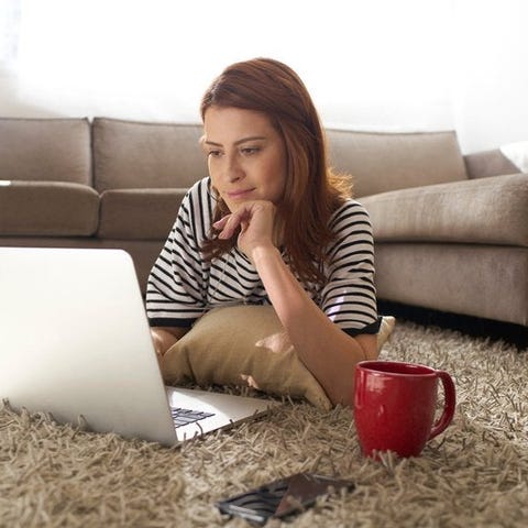 Woman using her laptop on her living room floor