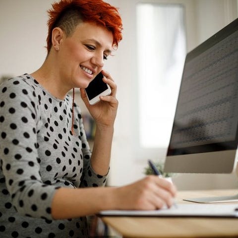 Woman working from home using computer, phone, and