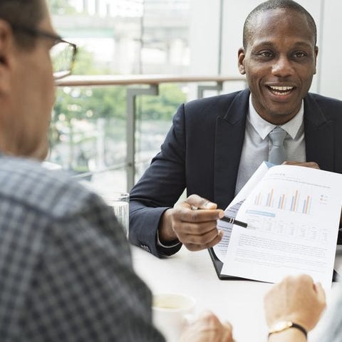 mature man and woman sitting at desk talking to ma