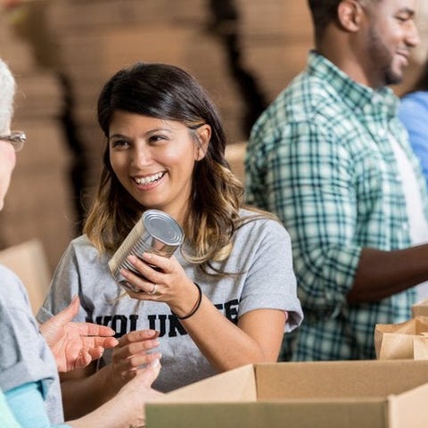 A group of smiling volunteers packing canned food 
