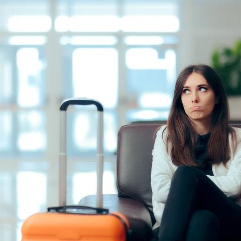 Disappointed woman sitting in airport chair next t