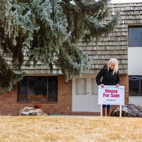 A person putting a House for Sale sign in the fron